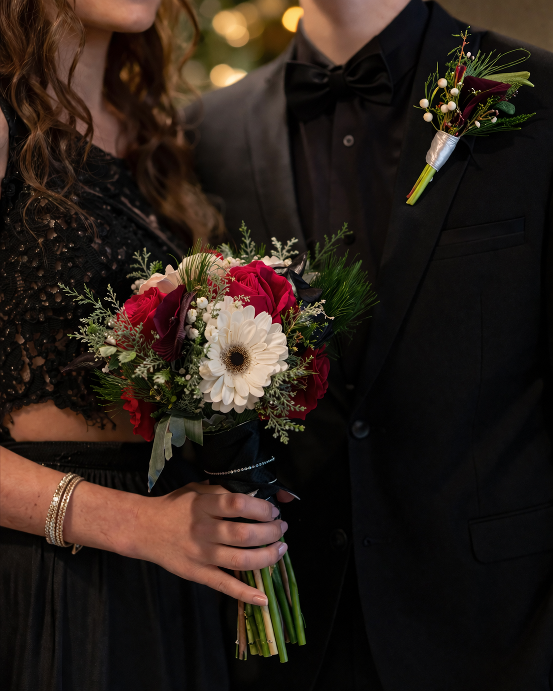 Prom bouquet and boutonniere set from a Canonsburg, PA florist featuring red, white, and greenery flowers, styled with a black dress and tuxedo.